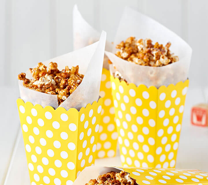 Caramel spiced popcorn in a yellow and white polkadot container